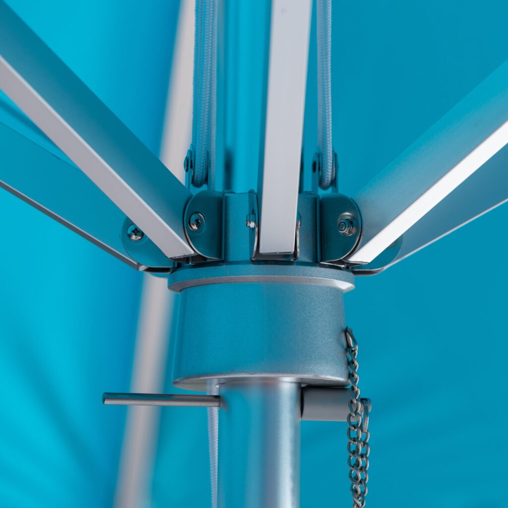 Close-up of BAJAMATE umbrella hub showing heavy-duty aluminum ribs bolted into a reinforced central housing on a 2-inch pole