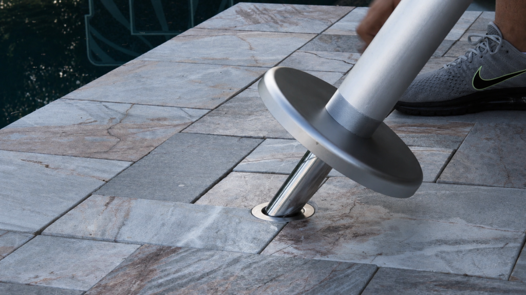 BajaMate adapter pin sliding into a stainless steel pool sleeve installed in travertine