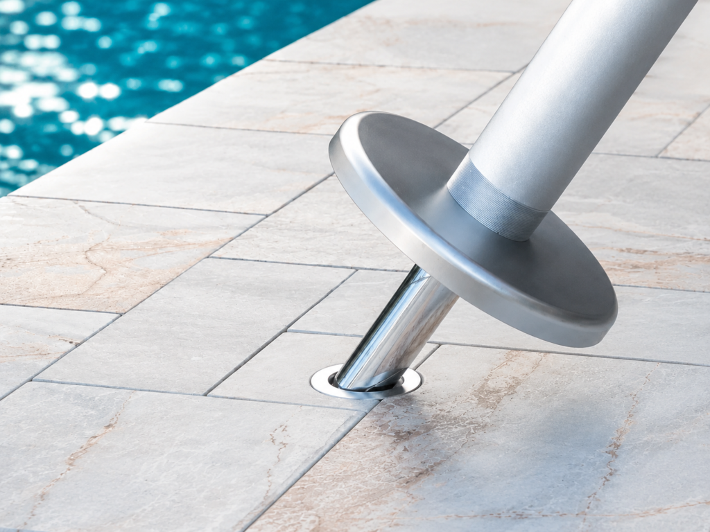 BajaMate Anchor adapter being inserted into a stainless steel pool umbrella sleeve installed flush in a stone pool deck.