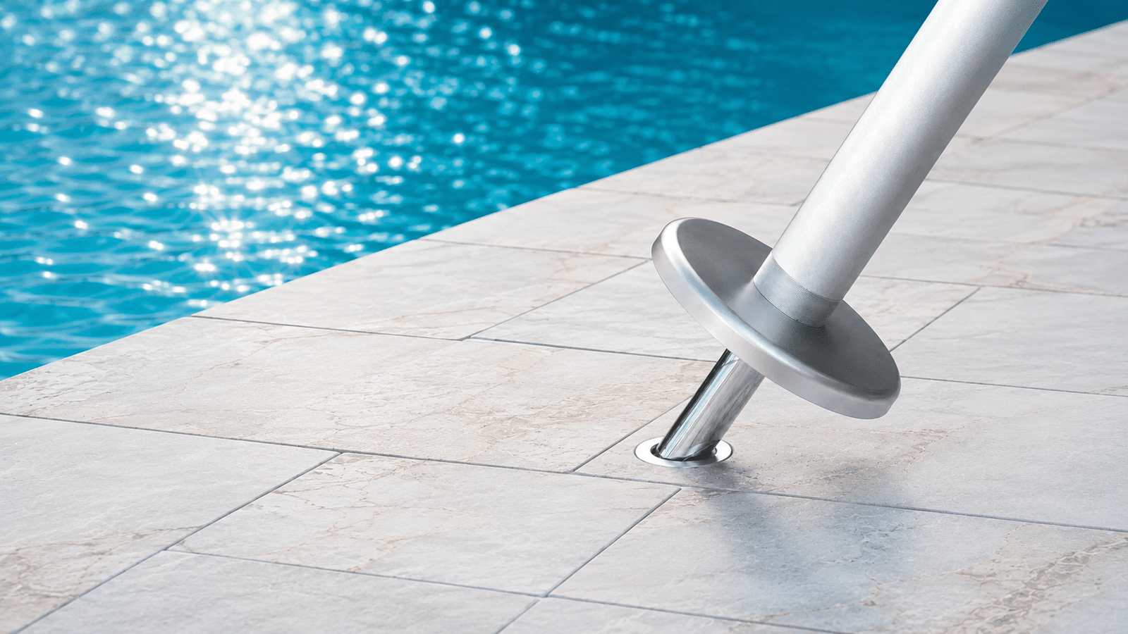 BajaMate aluminum anchor adapter sliding into a stainless steel pool deck sleeve beside a swimming pool.